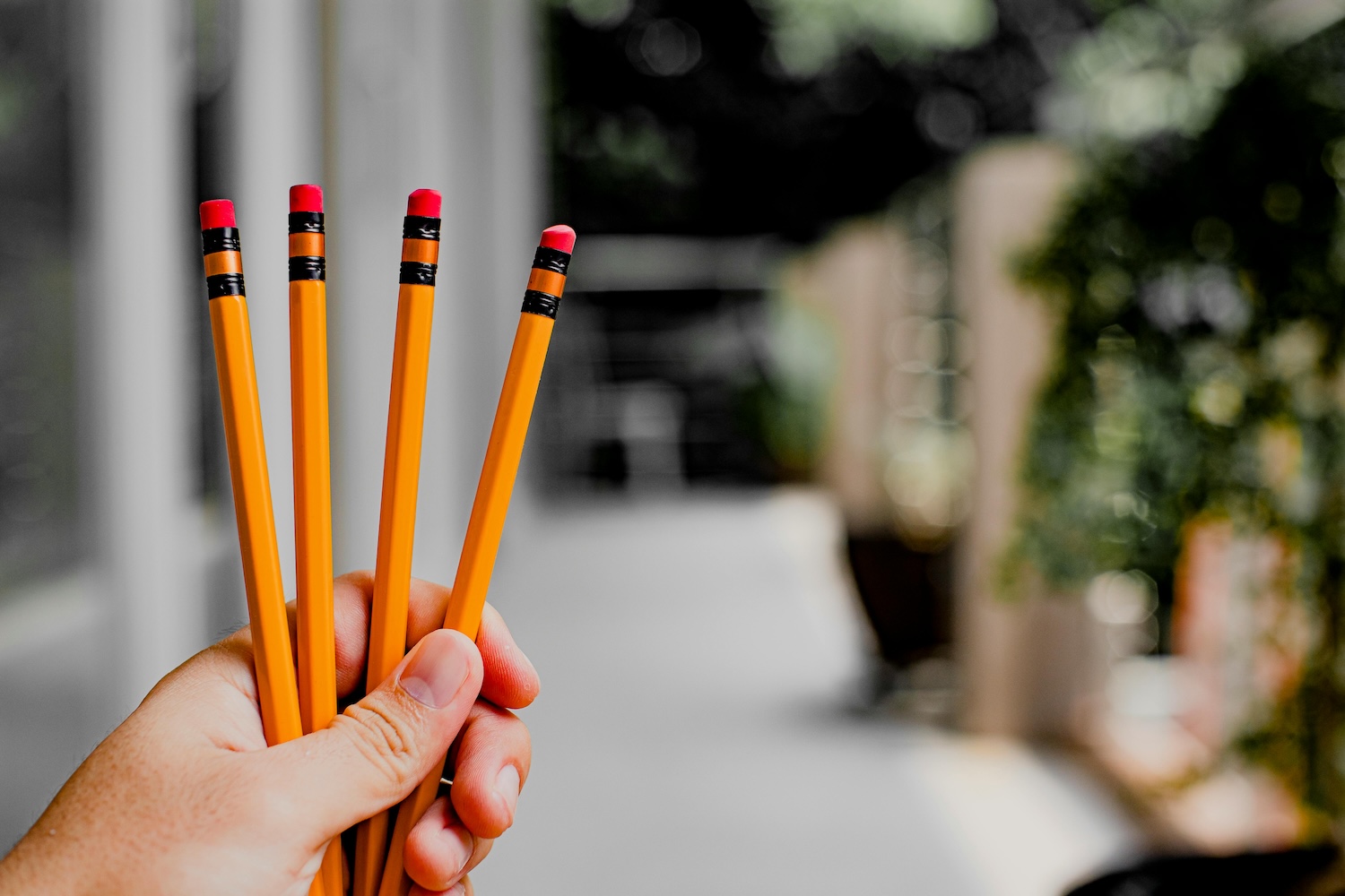 a hand holding 4 pencils