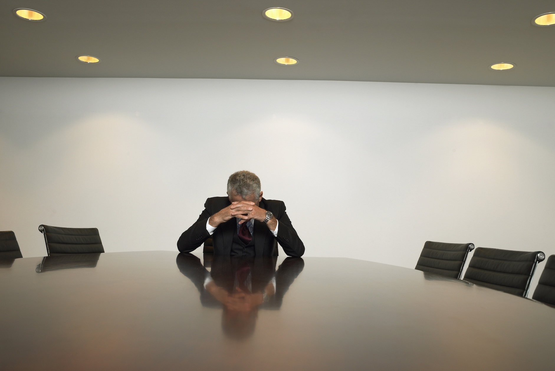 frustrated man sitting alone at conference table