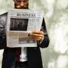 Man in a suit reading the Business section of a newspaper