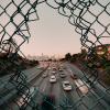 Breaking through a fence to see cars speeding on a road