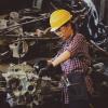 Woman wearing a hard hat and working with a machine