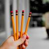 a hand holding 4 pencils