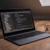 laptop on a workspace with code on the screen